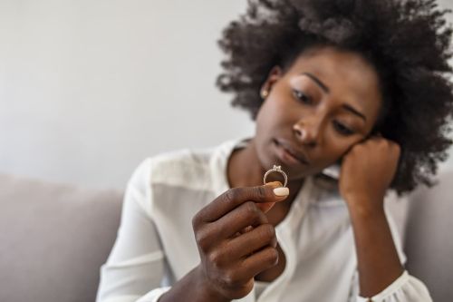 Upset african American girl hold wedding ring cry depressed with divorce
